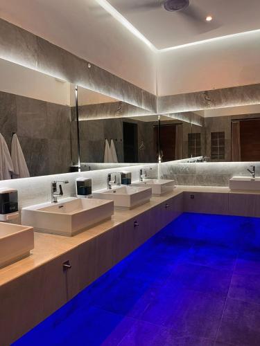 a large bathroom with three sinks and blue lights at Spartacus hostel boutique for men in Puerto Vallarta