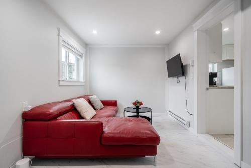 a red couch in a living room with a tv at Cozy and Modern 2br guesthouse in Vancouver