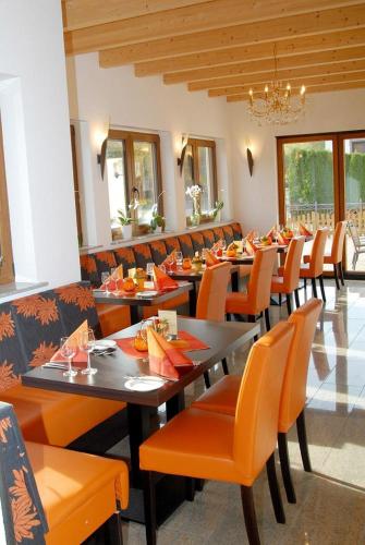 a dining room with long tables and orange chairs at Hotel-Restaurant Laux in Merzig