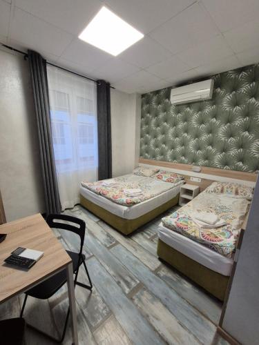 a room with two beds and a table and a desk at Guest House "The House" Топ Център Габрово in Gabrovo