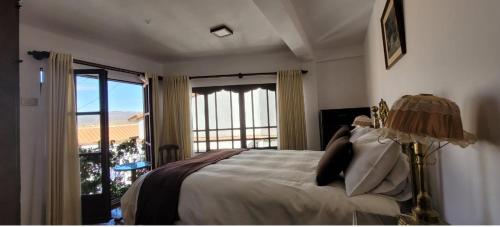 a bedroom with a bed and a large window at El Jardin De Su Merced B&B in Sucre