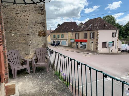 zwei Stühle auf einem Balkon neben einer Straße in der Unterkunft Pantouflard - Maison entière in Toucy