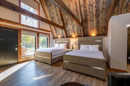 two beds in a room with wooden walls at Cove Creek Lodge 211 Standard Double Queen Fireplace Room in Oakland