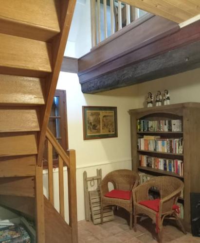 a room with two chairs and a book shelf with books at Chez Johns in Bailleul-Neuville