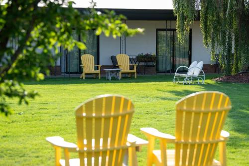 three chairs sitting in the grass in a yard at Sapphire Motel Midtown Bozeman in Bozeman
