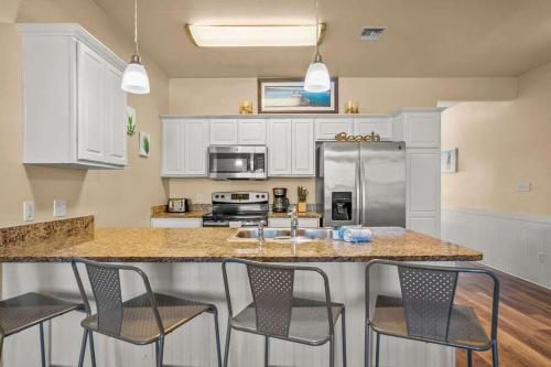 a kitchen with a counter with chairs and a refrigerator at 3 Br Padre Isl Retreat Min to Beach Dog Friendly in Padre Island