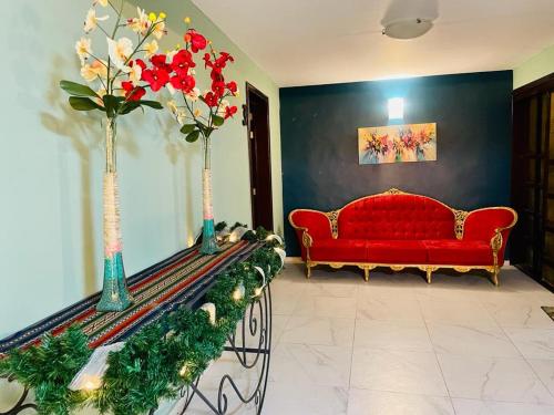 a living room with a red couch and vases with flowers at Casa Hotel Marchel in Tequila