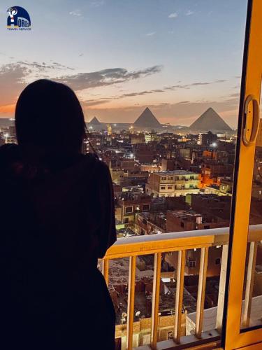 a person looking out of a window at a city at Horus The Horizon Pyramids View in Cairo