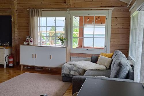Una sala de estar con un sofá y dos ventanas. en Hirsimökki harjulla, en Pudasjärvi