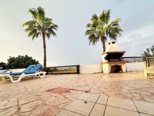 a couple of chairs and palm trees in a patio at Sunset Pearl Holiday Villa in Ayia Napa