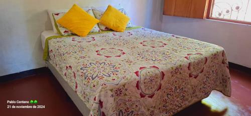 a bedroom with a bed with a flowered blanket and yellow pillows at Valentina's House in Rivas