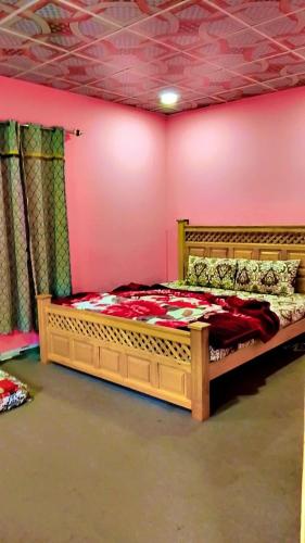 a bedroom with a wooden bed in a pink wall at Neelum View guest House in Dargai