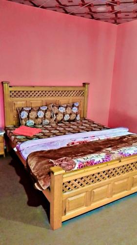 a wooden bed in a room with a pink wall at Neelum View guest House in Dargai
