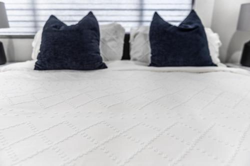 a white bed with blue pillows on top of it at 50 M to Sand LGB 2 King Suites in Long Beach