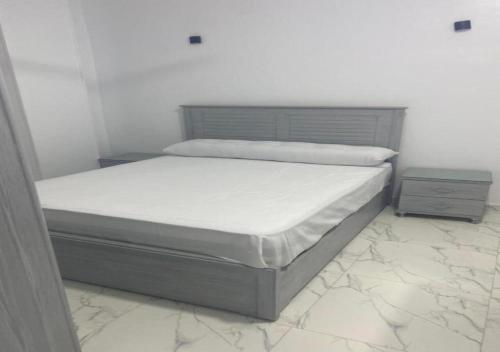 a white bedroom with a bed and a night stand at Alara Hostel ' Only girls ' in Naj‘ al Maḩaţţah