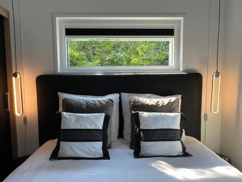 a bed with two pillows and a window above it at Qué Vida, Boutique Chalet aan Zee en Meer in Scharendijke