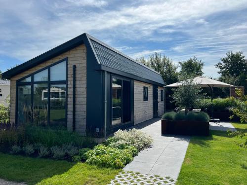 a small house with glass doors in a garden at Qué Vida, Boutique Chalet aan Zee en Meer in Scharendijke