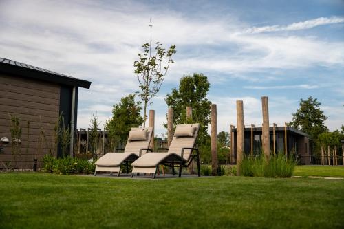 a group of white chairs sitting in a yard at Qué Vida, Boutique Chalet aan Zee en Meer in Scharendijke