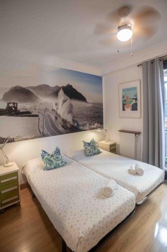 a bedroom with two beds and a painting on the wall at Gurtxu Rooms by Sun Sebastián in San Sebastián