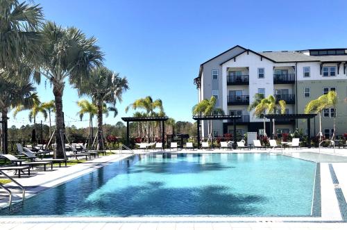 a swimming pool in front of a building with palm trees at Luxury Apartments Near Disney in Orlando