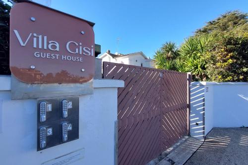 a sign for a villa guest house next to a fence at Villa Gisi Guest House in Fiumicino