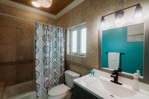 a bathroom with a sink and a toilet and a mirror at Private Oceanfront, beach, dock and Hottub - The Perky Pelican in Marsh Harbour