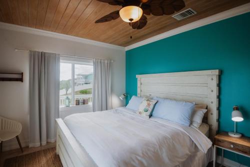 a bedroom with a white bed and a blue wall at Private Oceanfront, beach, dock and Hottub - The Perky Pelican in Marsh Harbour