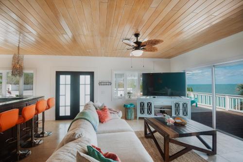 a living room with a couch and a tv at Private Oceanfront, beach, dock and Hottub - The Perky Pelican in Marsh Harbour