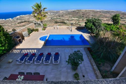 an aerial view of a swimming pool with chairs and the ocean at Ta Perelli in Żebbuġ