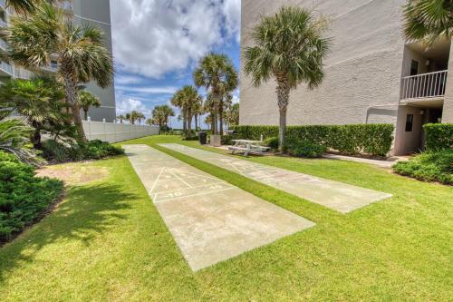 a walkway with a bench in a yard with palm trees at Seaside Beach & Racquet Club #4611 in Orange Beach