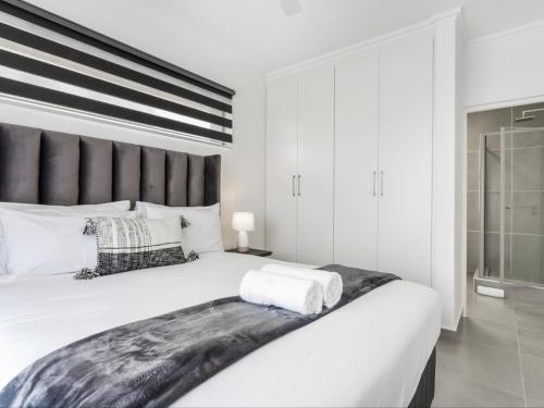 バリートにあるSpacious Ballito Village Apartmentのベッドルーム(白い大型ベッド1台、黒いヘッドボード付)