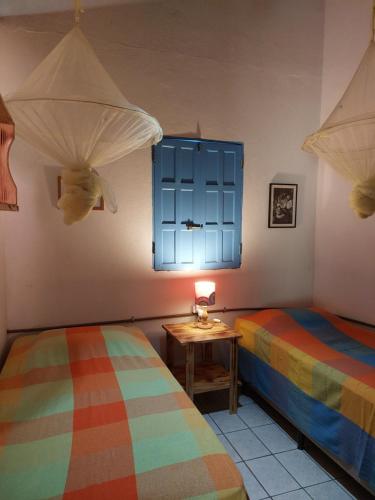 クムルサティバにあるCasa Passarinhosのベッドルーム1室(ベッド2台、青い窓付)