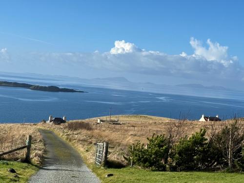 a road leading down a hill with a view of the ocean at Dunhallin Ard in Hallin