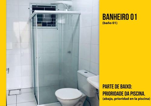 ein Badezimmer mit Toilette und Glasdusche in der Unterkunft Soares Acomodações in Itapema