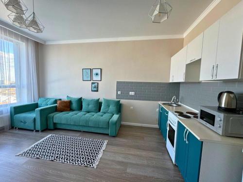 a living room with a blue couch in a kitchen at Nexpo City уютные апартаменты возле ЭКСПО in Prigorodnyy