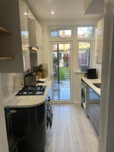 a kitchen with a stove top oven next to a door at Modern home with driveway parking for 2 vehicles, near Tottenham Hotspur Stadium, White Hart Lane Train Station in London