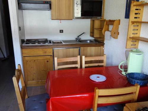une petite cuisine avec une table rouge et une table rouge dans l'établissement Résidence Maison De L'alpe - APPARTEMENT ALPE D'HUEZ QUARTIER VIEL ALPE MAE-2041, à Huez