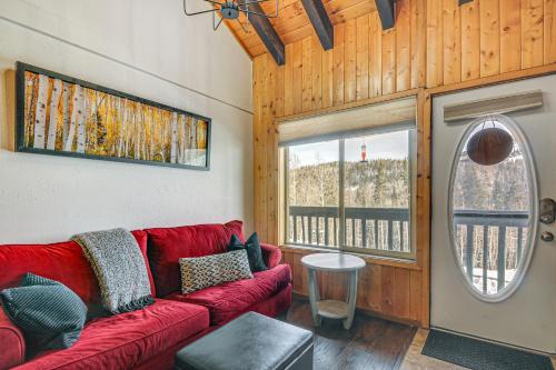 a living room with a red couch and a window at Brian Head Condo Walk to Giant Steps Ski Lifts! in Brian Head