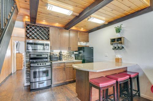 a kitchen with wooden cabinets and a counter with red stools at Brian Head Condo Walk to Giant Steps Ski Lifts! in Brian Head