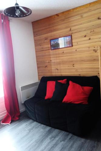 - un canapé noir avec 2 oreillers rouges dans l'établissement Résidence Skisud - APPARTEMENT ALPE D'HUEZ QUARTIER BAS DE STATION MAE-2151, à Huez
