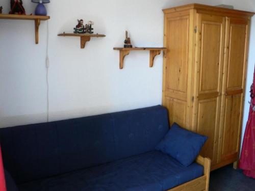 - un canapé bleu dans une chambre avec une armoire en bois dans l'établissement Résidence Soleil D'huez - APPARTEMENT ALPE D'HUEZ QUARTIER DE L'ECLOSE MAE-2281, à Huez