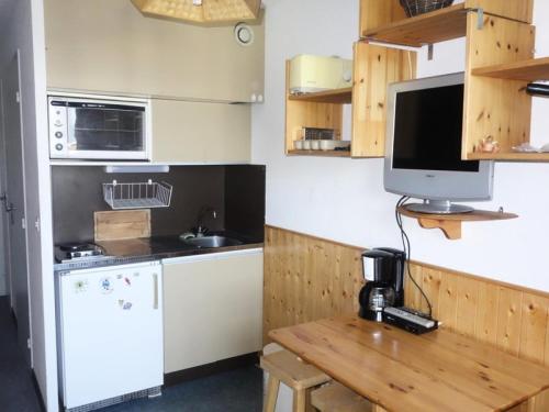 Il comprend une cuisine avec une table et une télévision murale. dans l'établissement Résidence Soleil D'huez - APPARTEMENT ALPE D'HUEZ QUARTIER DE L'ECLOSE MAE-2281, à Huez