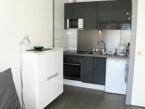 une cuisine avec des appareils en noir et blanc et une lampe dans l'établissement Résidence Samovar - APPARTEMENT ALPE D'HUEZ QUARTIER CENTRE STATION MAE-2291, à Huez