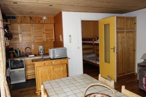 - une petite cuisine avec des placards en bois et un four micro-ondes dans l'établissement Résidence Lupins - APPARTEMENT ALPE D'HUEZ CENTRE STAITON MAE-2311, à Huez