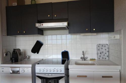 - une cuisine avec des placards noirs, un évier et une cuisinière dans l'établissement Résidence Montana - APPARTEMENT ALPE D'HUEZ HAUT DE STATION MAE-2331, à Huez