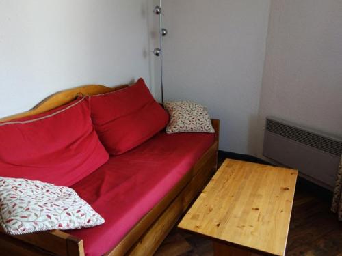 - un canapé rouge avec deux oreillers et une table en bois dans l'établissement Résidence Bergers P&v - APPARTEMENT ALPE D'HUEZ QUARTIER BERGERS MAE-2371, à Huez
