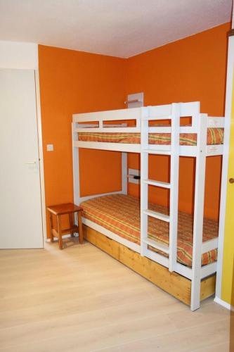 Ce lit se trouve dans un dortoir doté de 2 lits superposés et d'un mur orange. dans l'établissement Résidence Maeva Les Melezes - APPARTEMENT ALPE D'HUEZ QUARTIER BERGERS MAE-2391, à Huez