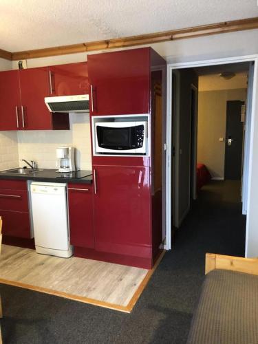 une cuisine avec des armoires rouges et un micro-ondes dans l'établissement Résidence Bergers P&v - APPARTEMENT ALPE D'HUEZ QUARTIER BERGERS MAE-2381, à Huez