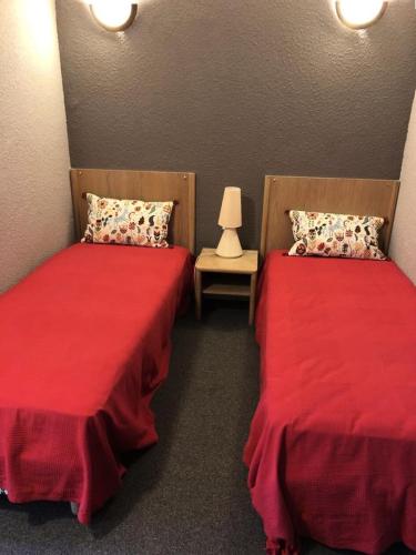 2 lits dans une chambre avec des draps rouges et une lampe dans l'établissement Résidence Bergers P&v - APPARTEMENT ALPE D'HUEZ QUARTIER BERGERS MAE-2381, à Huez