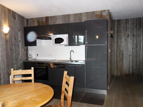 La cuisine est équipée d'une table, d'un évier et d'un réfrigérateur. dans l'établissement Résidence Taburle - APPARTEMENT ALPE D'HUEZ HAUT DE STATION MAE-2421, à Huez